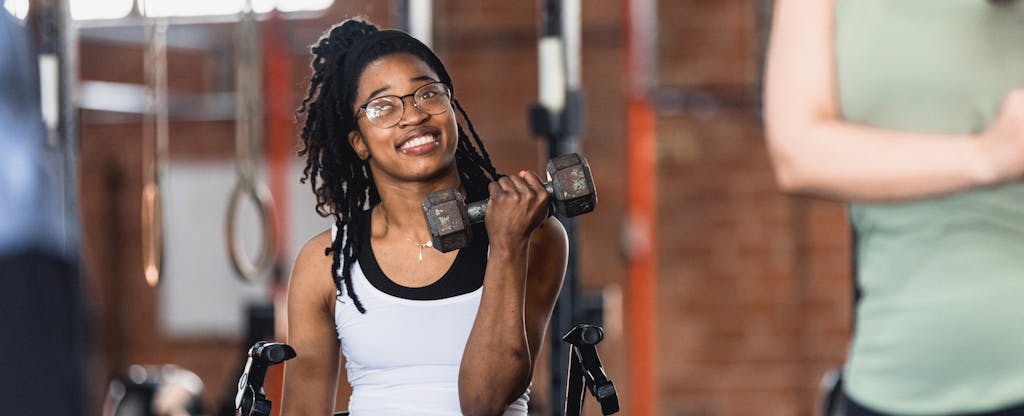 Woman using a wheelchair, lifting weights at the gym and smiling