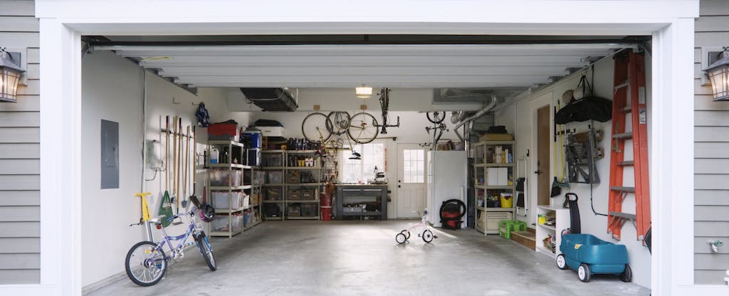 A newly built garage with fresh paint, organized shelves, gardening tools and several bicycles.