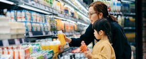 A parent and child check the prices on fruit juice at the grocery store