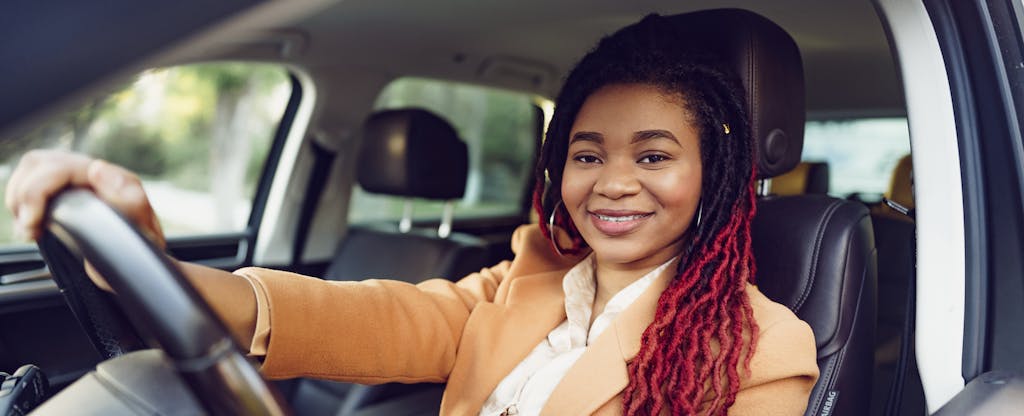 Young black woman behind the wheel of her car, smiling