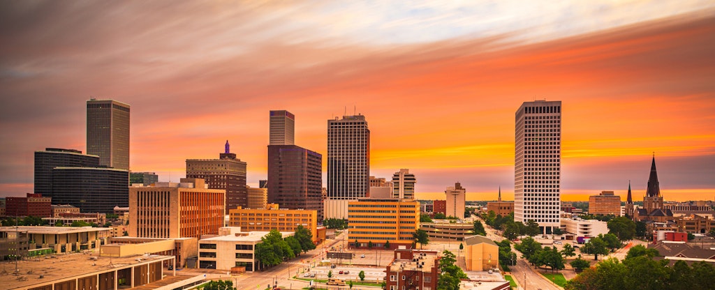 The Tulsa, Oklahoma, downtown skyline against an orange hued sky at twilight