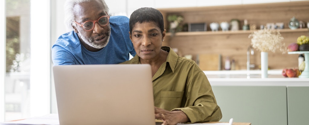 A couple at home use a laptop to review their assets and determine their net worth.