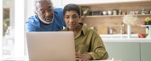A couple at home use a laptop to review their assets and determine their net worth.