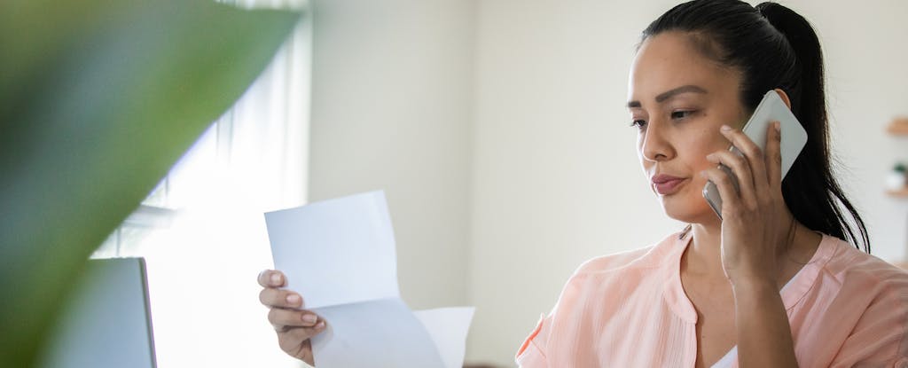 image of concerned woman on the phone, with her student loan bill in hand