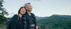 Retired couple on a hike, happily enjoying the view of the lush valley around them