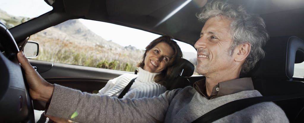 Smiling couple driving in a car while on a road trip