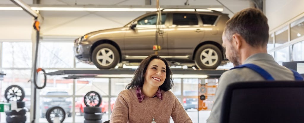 Woman talks with salesperson at a car shop.