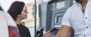 Woman using credit card to pay for gas at a gas station.