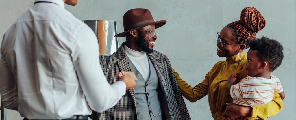 Concierge handing a happy couple their credit card in a hotel lobby.