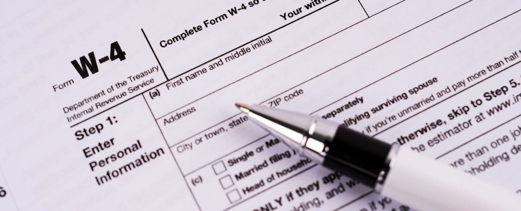 A close up image of a printed W-4 form with a ball point pen resting on top.