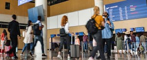 Diverse people heading tor a check in at the airport. Holding luggage and boarding passes.