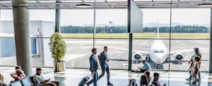 A bright and airy airport terminal bustling with activity during the day, as diverse people of all ages are patiently waiting for their flights.