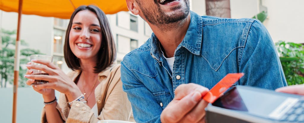 Young adult man and woman couple paying the bill with a contactless credit card at a restaurant, bar or coffee shop.