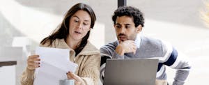 A couple is organizing and estimating their expenses while collecting bills and summarizing them to control and set their expenses in an online financial management app.