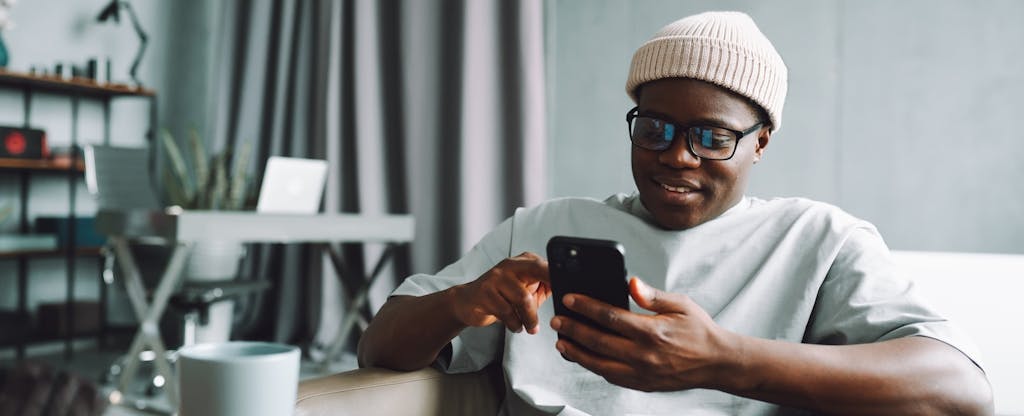 Online shopping. A man makes purchases on the Internet using a smartphone at home in the living room.