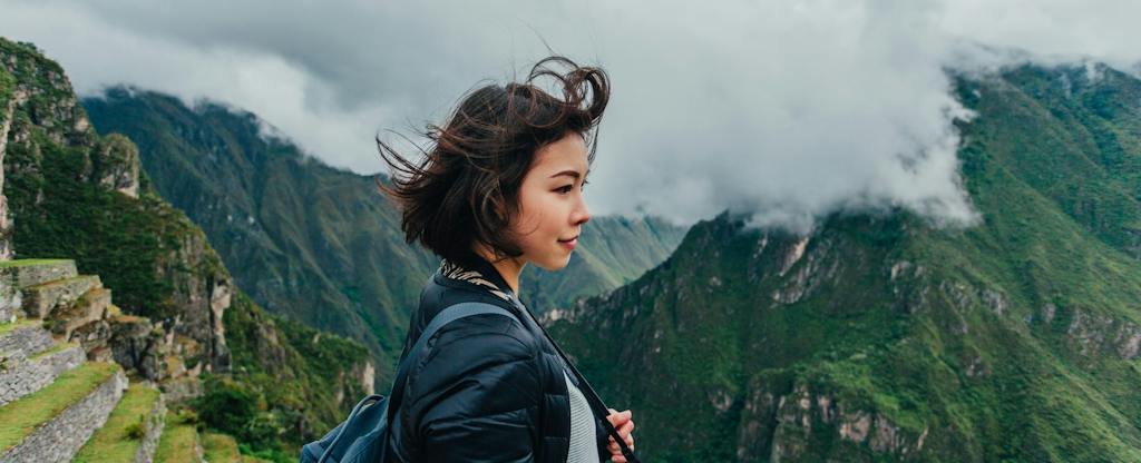 how-to-maximize-credit-card-rewards Young woman looking at view from the Machu Picchu mountains in Peru.