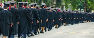 The rear view of graduates in traditional caps and gowns, symbolizing the culmination of their academic journey.